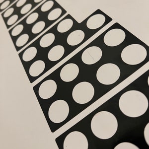 May include: Black and white sticker sheet with a design of a series of circles arranged in a decreasing size pattern.