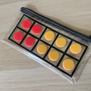 May include: A clear plastic zipped pouch with a grid pattern printed on the inside. The pouch contains red and yellow circular counters.