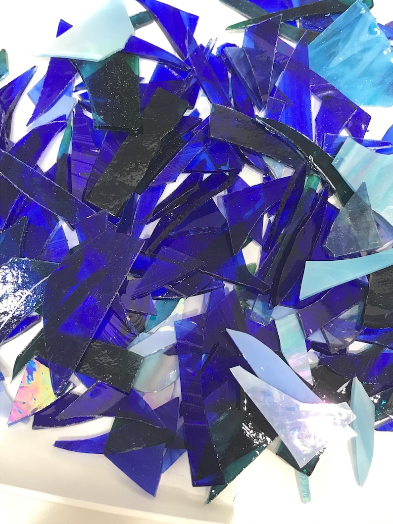 Op de afbeelding: Een stapel blauwe en iriserende glasscherven, perfect voor knutsel- of moza&iuml;ekprojecten.
