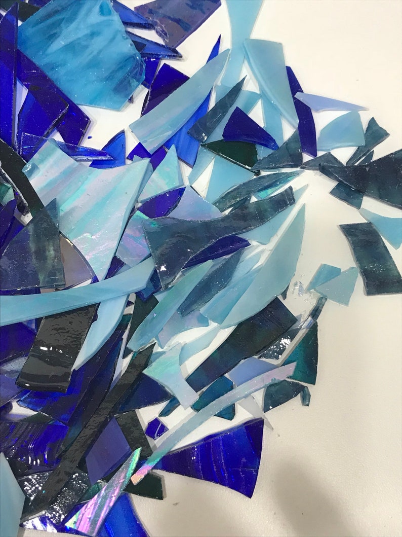Op de afbeelding: Een stapel blauwe en iriserende glasscherven, perfect voor knutsel- of moza&iuml;ekprojecten.
