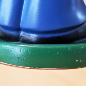 May include: A vintage figurine with a blue top, black accents, and a green base. The base has embossed text that reads "Walt Disney Inc." and "Ideal Plastics Corp."