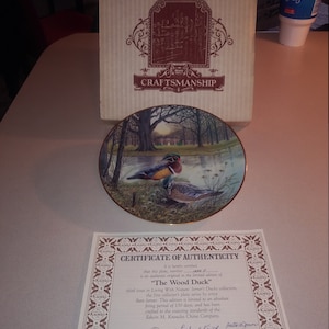 May include: A certificate of authenticity for a limited edition collector's plate featuring a wood duck. The plate is part of the "Living With Nature: Jemer's Ducks" collection by artist Bart Jemer. The certificate is signed by Richard Keith, Vice President, and Betty J. Green, Artist.