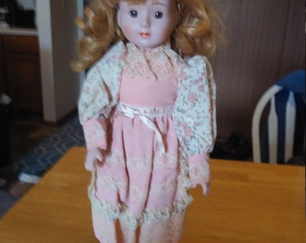 Porcelain Doll #120 with lace, pink and floral outfit. Circa. 1980s with wooden and metal stand up stand.