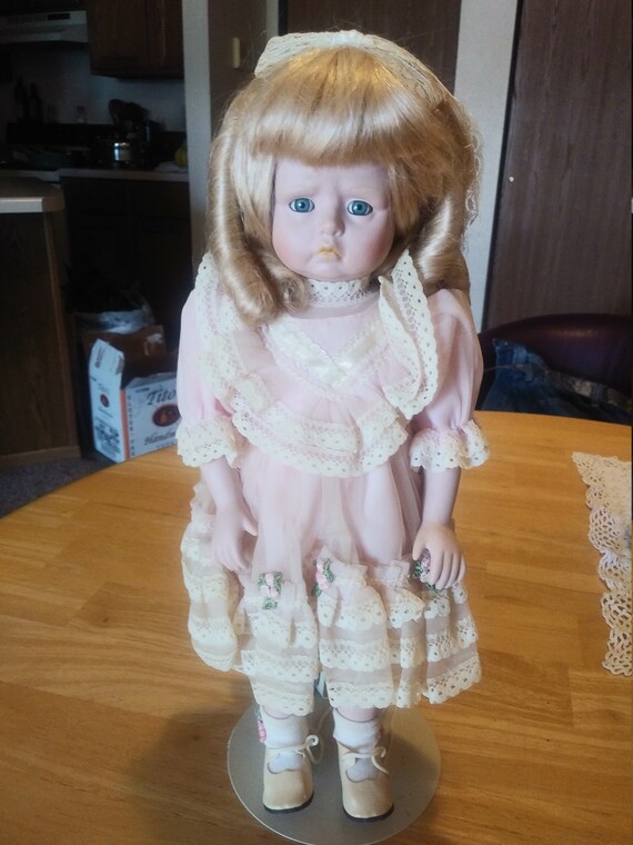 Porcelain Doll # 206 with pink dress and lace with little flowers on it Circa. 1970s comes with stand.
