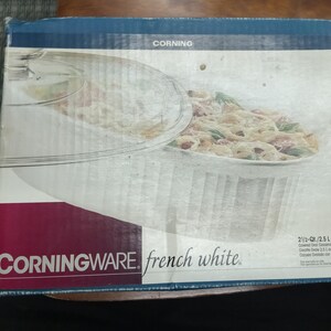 May include: A white Corningware French White 2.5 liter covered oval casserole dish with a glass lid. The box shows the dish with a serving of pasta.