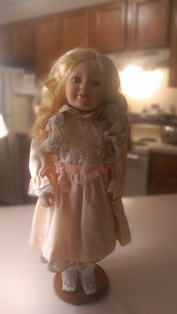 Porcelain doll # 11 orange dress with white and orange lase. Some floral embroidery on the front of doll too. Circa. 1980s.
