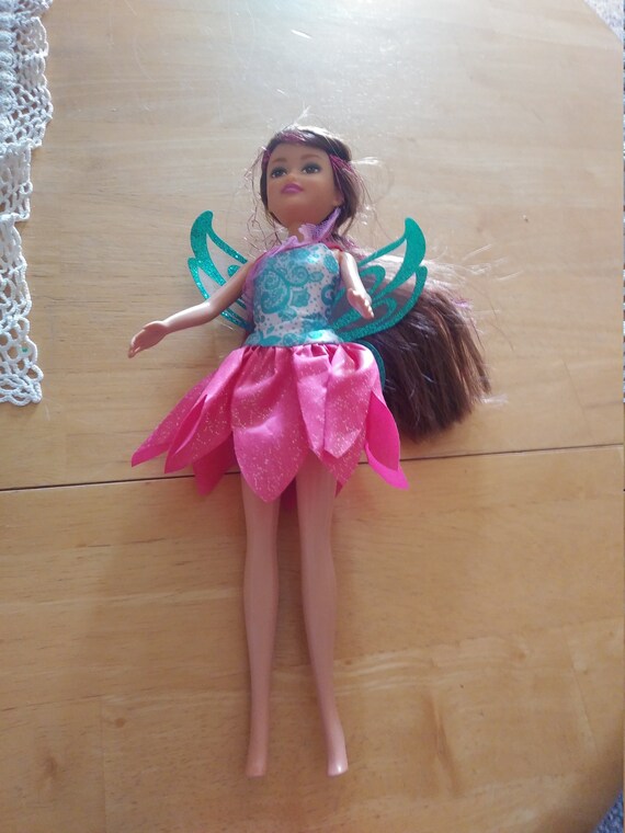 Doll wearing a blue and white top with a pink sequined bottom of the dress. Circa. 2000