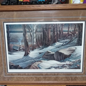 May include: Framed print of a winter scene with a deer in the woods. The print is titled "Winter's Edge" and is signed by the artist.