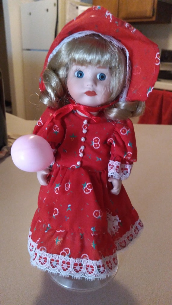 Porcelain doll # 39 in red dress with white lace holding a pink ballon circa 1980s.