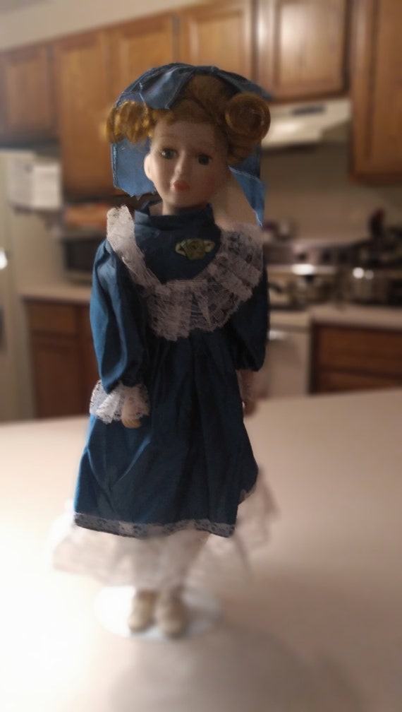 Porcelain doll # 17 with a teal green satin dress with white lace. Circa. 1980s