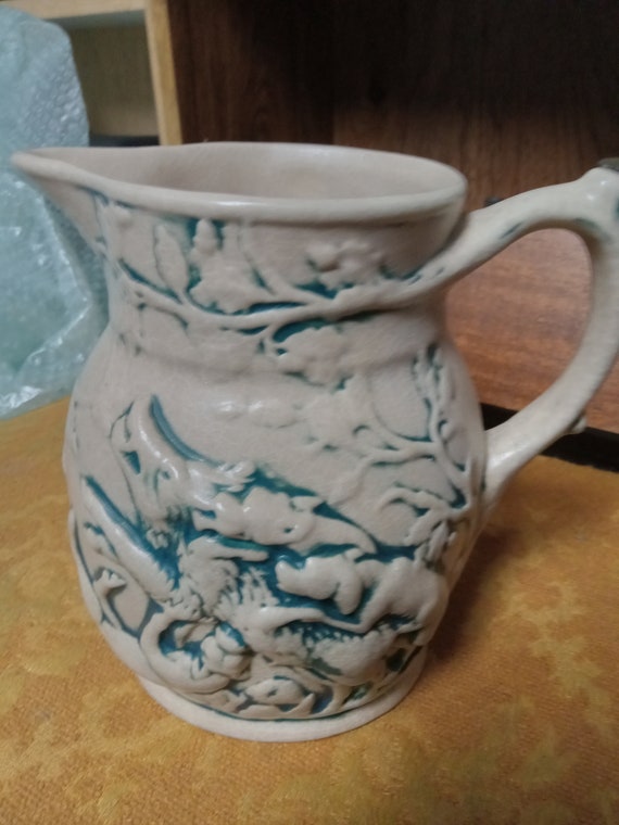 Blue washed embossed pottery pitcher