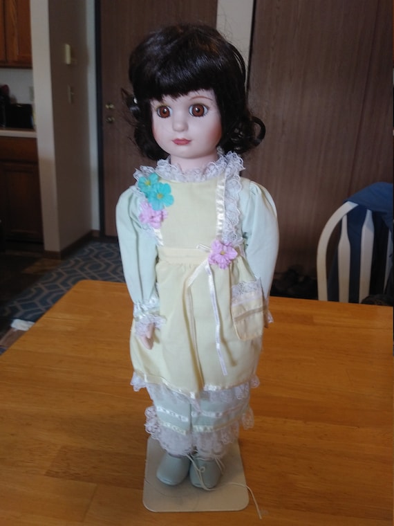 Porcelain Doll # 122 with yellow and green floral dress with lace circa. 1980s. With stand.
