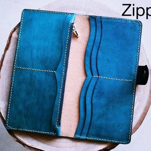 May include: A teal leather wallet with a zipper closure and multiple card slots. The wallet is open and the interior is visible.