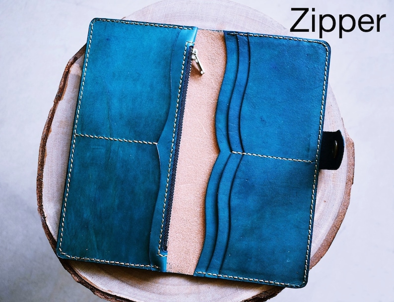 May include: A teal leather wallet with a zipper closure and multiple card slots. The wallet is open and the interior is visible.