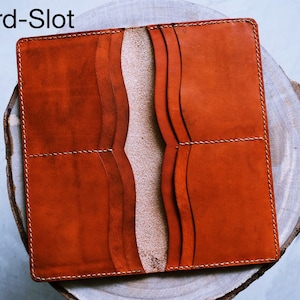 May include: A brown leather wallet with multiple card slots and a fold-over closure. The wallet is open to show the interior card slots.