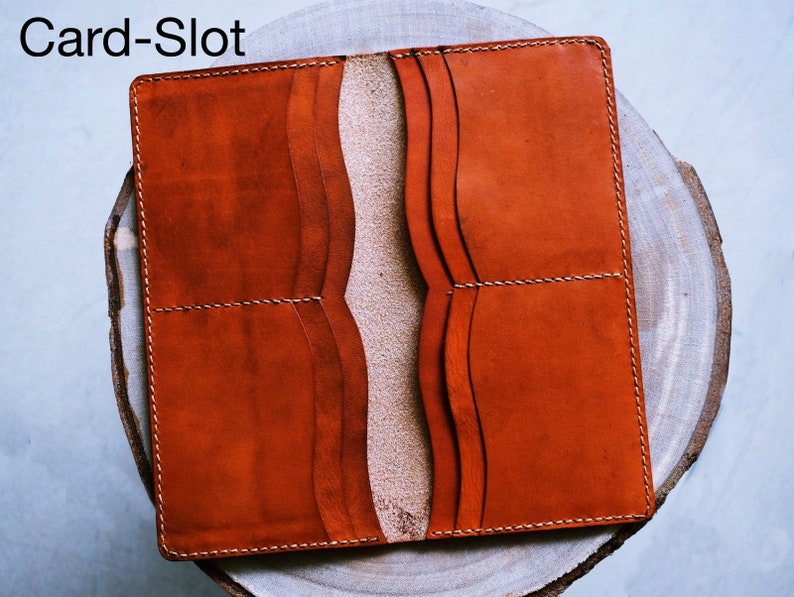 May include: A brown leather wallet with multiple card slots and a fold-over closure. The wallet is open to show the interior card slots.