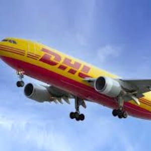 May include: A yellow and red DHL cargo airplane in flight against a blue sky. The plane has two engines and the DHL logo is prominently displayed on the side of the fuselage.