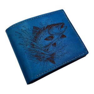 May include: A blue leather wallet with a brown fish design. The wallet is rectangular and features a detailed illustration of a fish jumping out of water. The edges are stitched with a contrasting thread.