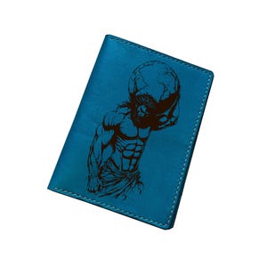 Pode incluir: Porta-passaporte em couro azul-petróleo com uma ilustração gravada a preto de Atlas segurando o mundo. Costuras brancas nas bordas. Um acessório de viagem elegante e funcional.