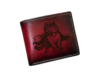 May include: A red leather wallet with a black and white illustration of a cat wearing a cape. The cat is looking to the left and has a collar with a bell.