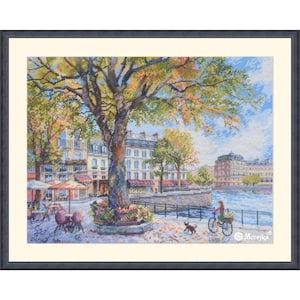 May include: A framed cross-stitch embroidery depicting a riverside city scene with a large central tree, outdoor cafe tables with umbrellas, a person riding a bicycle, and a small dog. The text Merejka is visible in the bottom right corner.