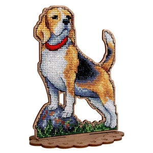 May include: A freestanding wooden cutout featuring a cross-stitch design of a beagle dog. The dog has brown, black, and white fur, a red collar, and stands on a small patch of green grass and a grey rock. The base is scalloped with paw prints.