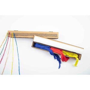 May include: A rectangular cardboard organizer box with a hinged lid featuring a row of numbered holes from 1 to 100. Inside the open box are bundles of blue, red, and yellow embroidery thread, with additional strands of thread extending outward.