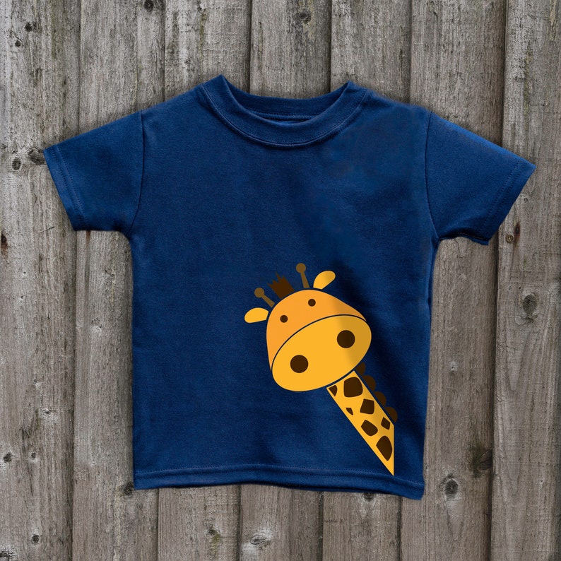 May include: A navy blue t-shirt with a cartoon giraffe peeking out from the side. The giraffe is yellow with brown spots and has a friendly face.