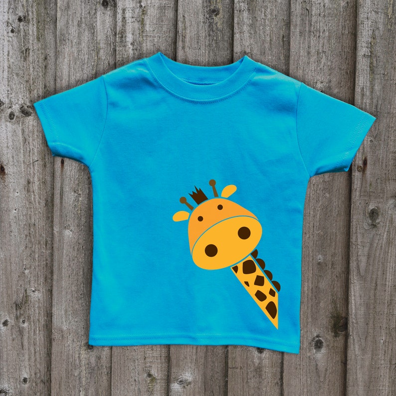May include: A bright blue t-shirt with a cartoon giraffe design. The giraffe is yellow with brown spots and has a friendly face.