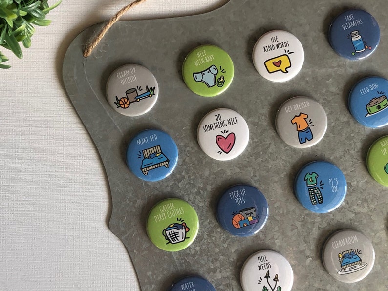 May include: A metal board with colourful round buttons featuring various chores and tasks for children. The buttons have illustrations and text such as "Clean Up Outside", "Help With Baby", "Make Bed", "Do Something Nice", "Use Kind Words", "Get Dressed", "Pick Up Toys", "Gather Dirty Clothes", "Pull Weeds", "Clean Room", "Feed Dog", "Take Vitamins", "P's On", "It's On".