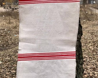 Puede incluir: Una toalla de té de lino blanco con rayas rojas y un borde de encaje blanco tejido a crochet.