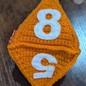 May include: Orange crocheted dice with white numbers 8 and 9.