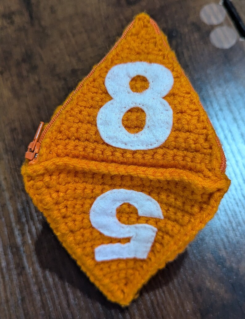 May include: Orange crocheted dice with white numbers 8 and 9.