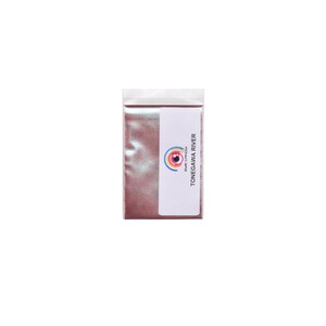 May include: A small, clear plastic bag filled with a shimmering, reddish-brown powder. A white label with the text "TONEGAWA RIVER" and a colorful eye logo is affixed to the bag. The bag is sealed at the top.