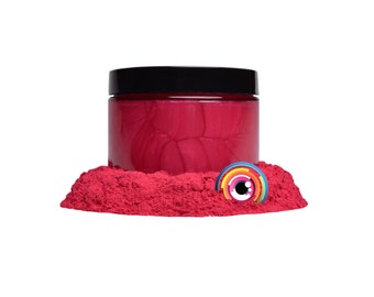 May include: A jar of bright pink mica powder with a black lid. The powder is piled around the jar, creating a small mound.