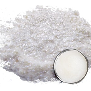 May include: A white iridescent glitter powder in a small round container. The powder is loose and has a shimmery finish.
