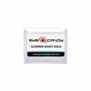 May include: A small white packet of glimmer ghost gold pigment from Eye Candy Customz. The packet has a black label with the company logo and the text "Glimmer Ghost Gold" and "www.eyecandy pigments.com".