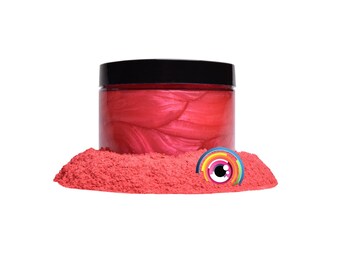 May include: A jar of red iridescent mica powder. The powder is in a clear jar with a black lid. The powder is surrounded by a pile of the same red mica powder.