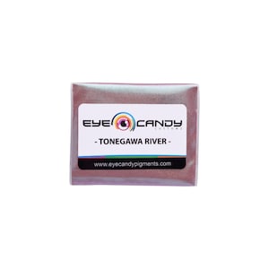 May include: A small, rectangular package of "TONEGAWA RIVER" eye candy pigments. The package has a white label with the brand name and a rainbow logo. The pigment inside appears to be a shimmering, reddish-brown color.