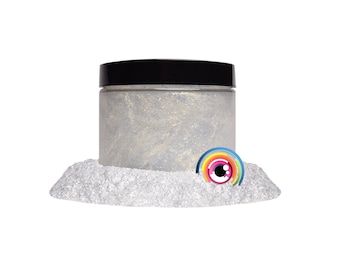 May include: A clear jar filled with iridescent glitter, with a black lid. The jar is sitting on a pile of white glitter. A colorful eye with a rainbow design is in front of the jar.