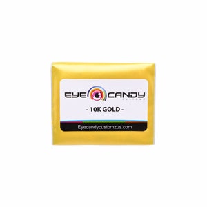 May include: A small, gold-colored package with the text "Eye Candy Customz" and "10K GOLD" on a white label. The website address "Eyecandycustomzus.com" is printed below the text.