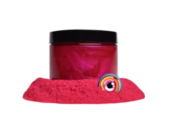 May include: A jar of bright pink iridescent mica powder. The powder is in a small pile in front of the jar.