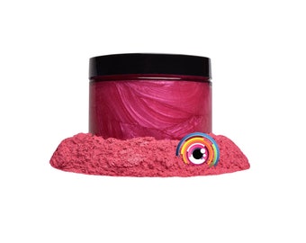 May include: A jar of pink iridescent mica powder with a black lid. The powder is in a pile on a white surface.