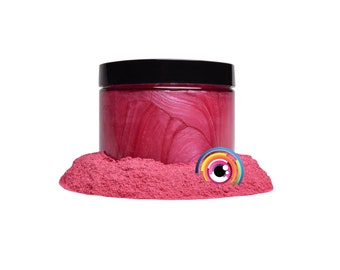 May include: A jar of pink iridescent mica powder with a black lid. The powder is in a pile on a white surface.