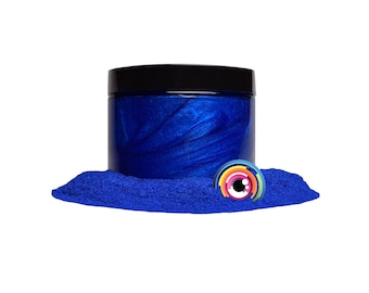 May include: A jar of blue metallic pigment powder. The powder is a vibrant blue with a metallic sheen. The jar is made of clear plastic and has a black lid.