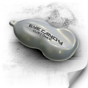 May include: A silver metallic paint sample with a pearlescent finish. The sample is shaped like a car bonnet and has the text "Eye Candy Customz" printed on it.