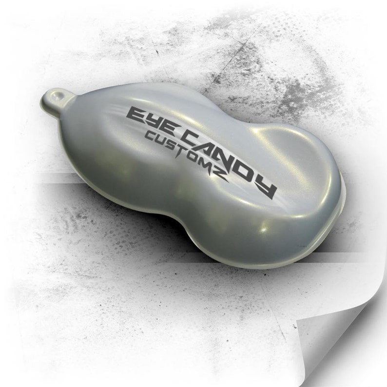May include: A silver metallic paint sample with a pearlescent finish. The sample is shaped like a car bonnet and has the text "Eye Candy Customz" printed on it.