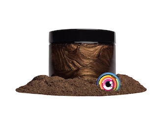 May include: A jar of brown metallic powder pigment with a black lid. The powder is spread out on a white surface.
