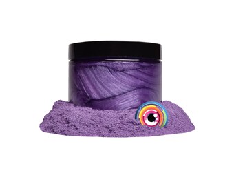 May include: A jar of purple iridescent mica powder with a black lid. The powder is in a small pile in front of the jar.