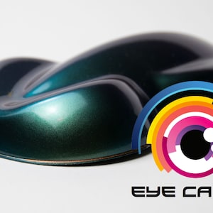 May include: A dark green and blue pearlescent paint sample with a metallic finish. The paint is displayed on a white background with the Eye Candy logo in the lower right corner.